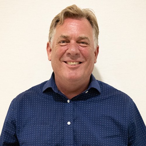 Professional headshot of a person wearing a blue patterned button-down shirt against a light background.