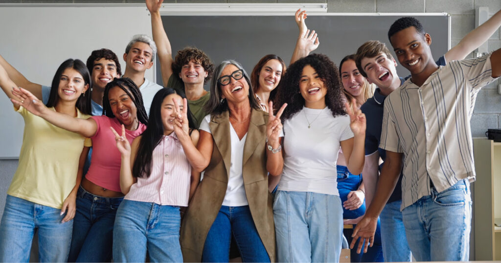 Group of students and an educator posing together in a classroom during a school celebration or activity.
