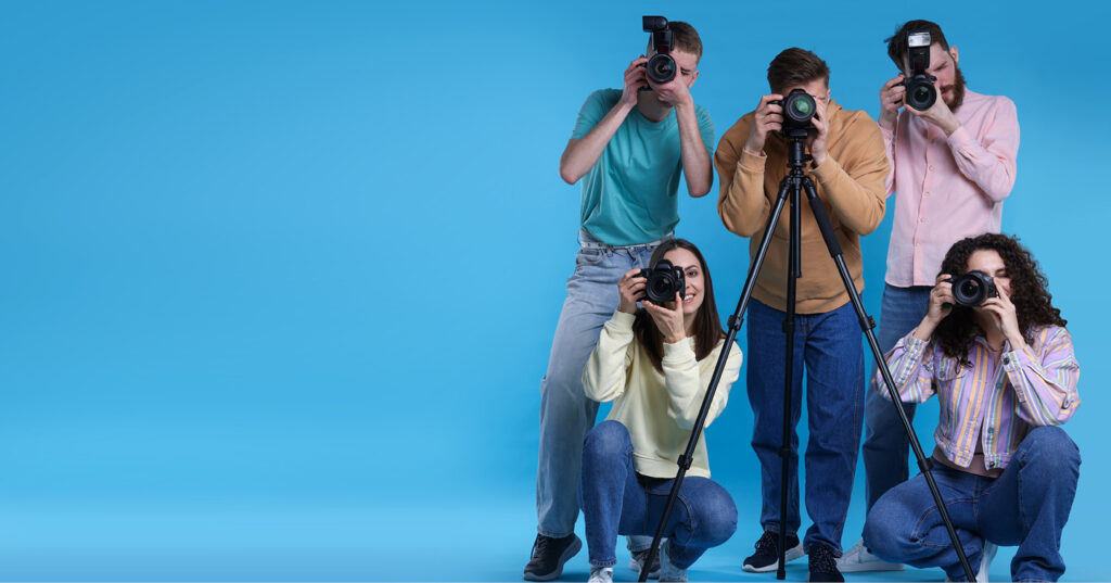 Group of student photographers using cameras and a tripod to capture photos during a photo shoot.