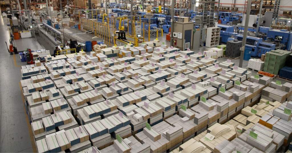 Large paper inventory staged across a manufacturing floor, with stacks of paper and printing equipment in operation.